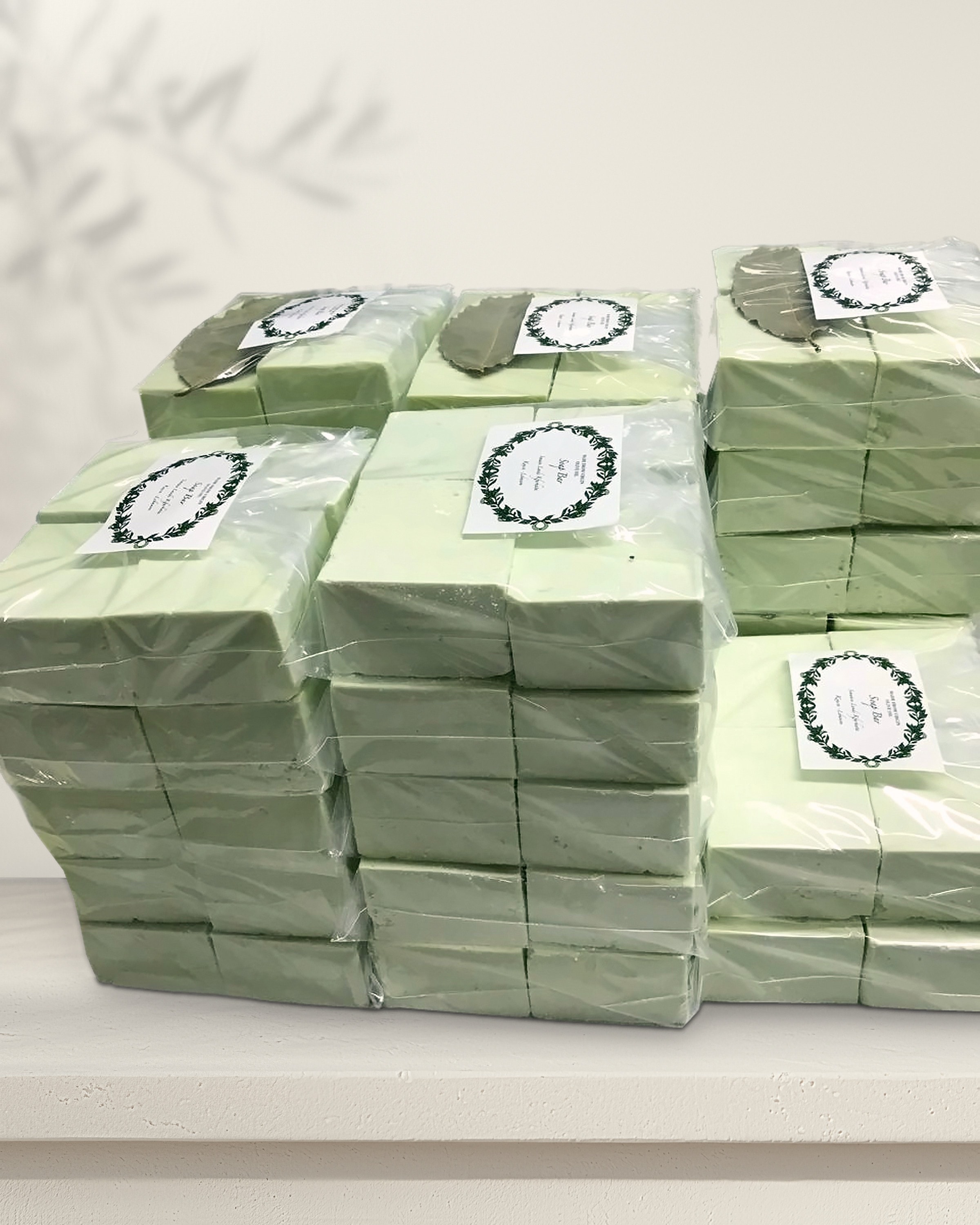 Stacks of our pale green olive-oil soap bars in clear film, each with our round label